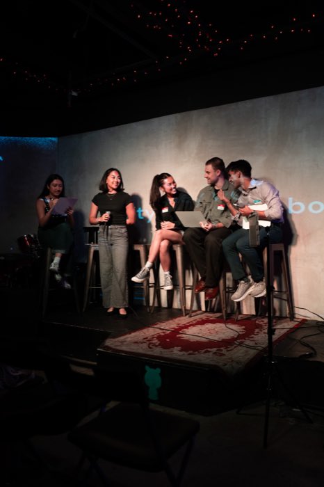 A crew laughing together on stage stools