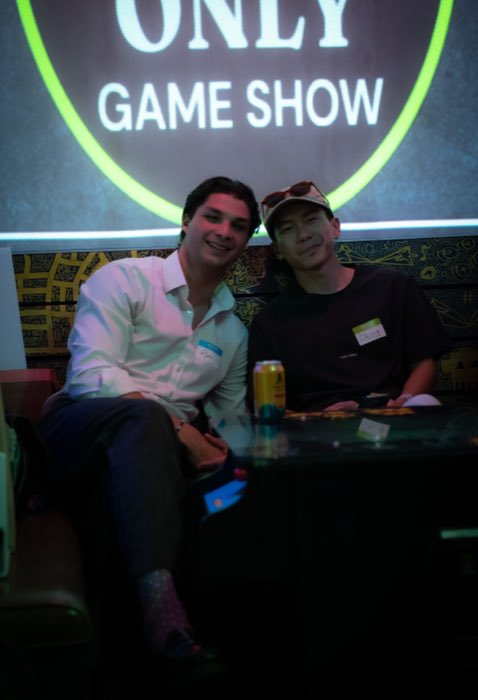 Two friends smiling under the Game Show projection